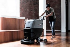A man cleaning the floor with a wireless scrubber drier.