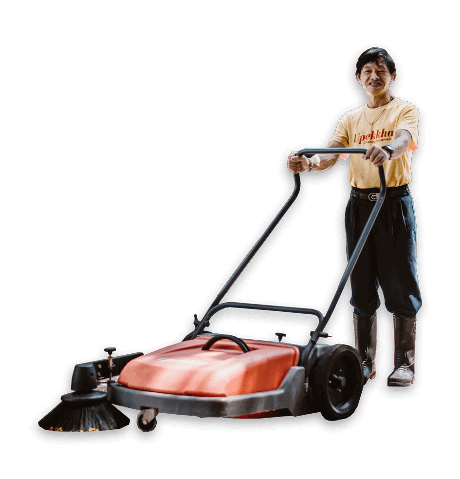 Upekkha personnel operating a Upekkha UpSweep Flipper+ push floor sweeper machine while smiling for the camera.