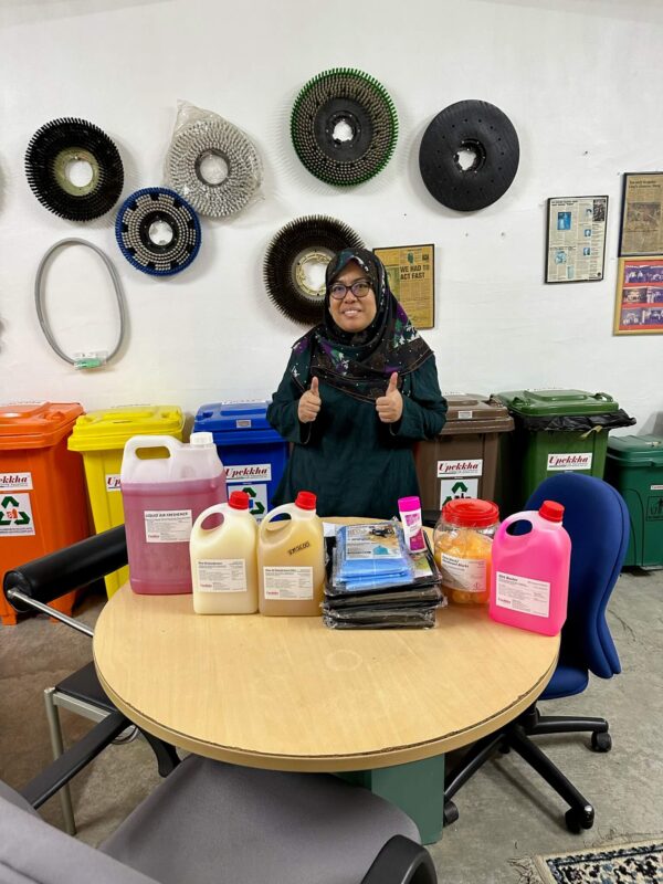 A woman smiling with her cleaning equipment and hygiene products purchase