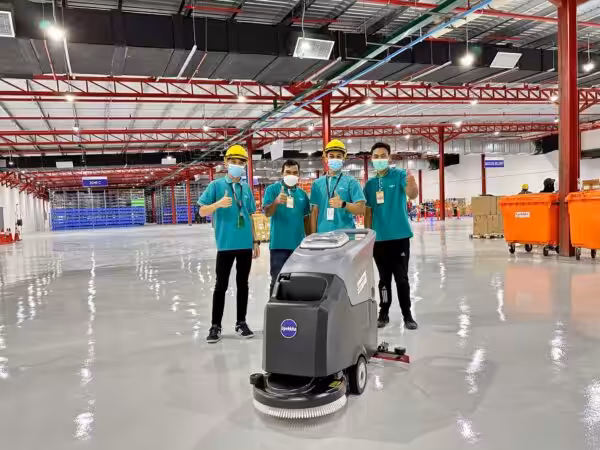 4 workers giving a thumbs up with a Upekkha auto scrubber machine.