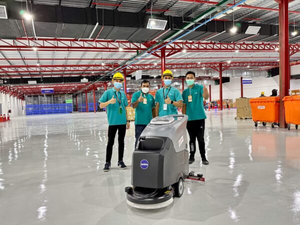Four workers giving a thumbs up with a Upekkha auto scrubber machine