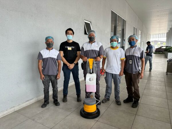 Five people with a Upekkha floor scrubber machine.