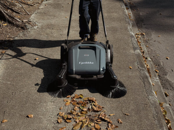 Person using a Upekkha mechanical floor sweeper outdoors