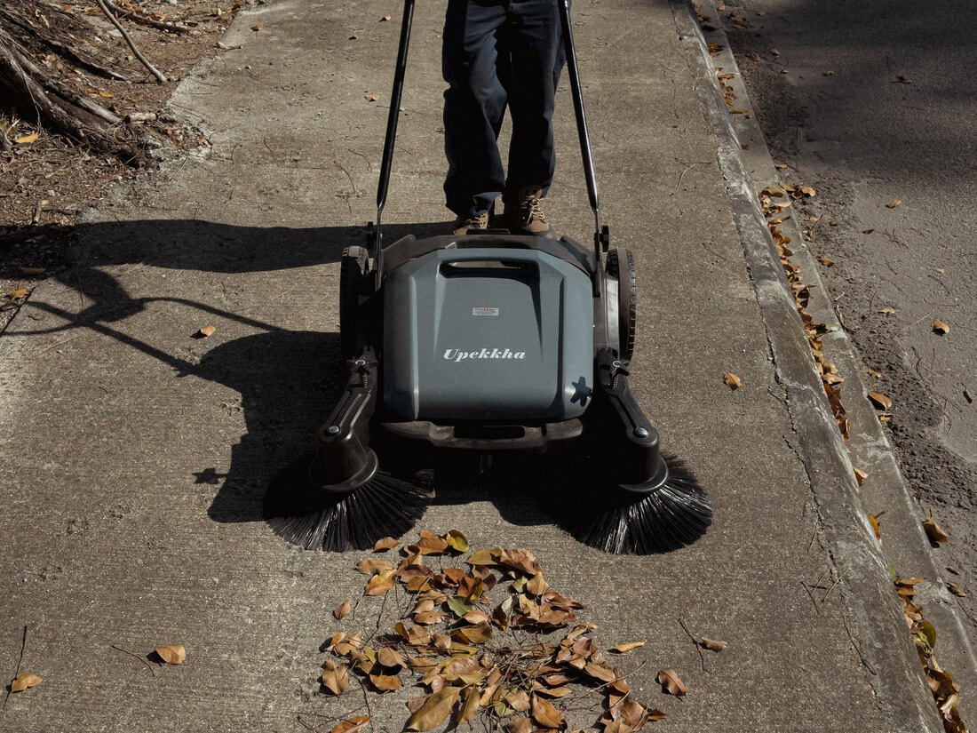 Person using a Upekkha mechanical floor sweeper outdoors