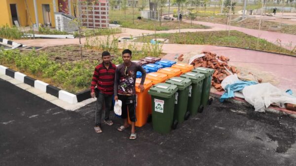 Two persons with rows of Upekkha garbage and recycle bins